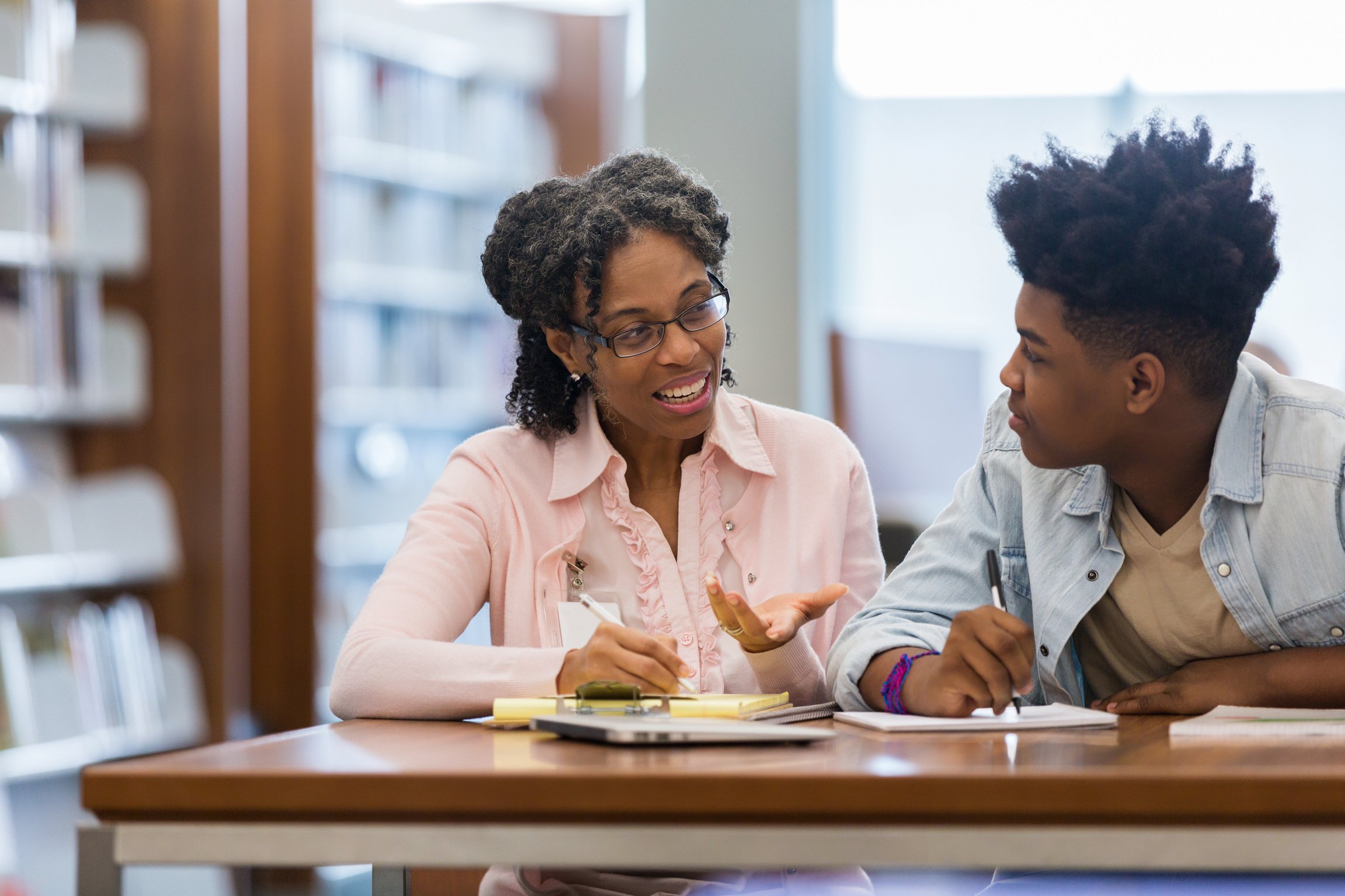 Volunteer mentors teen boy in school library